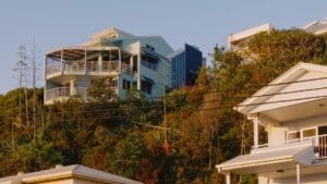 Coastal hillside homes surrounded by greenery in warm evening light.